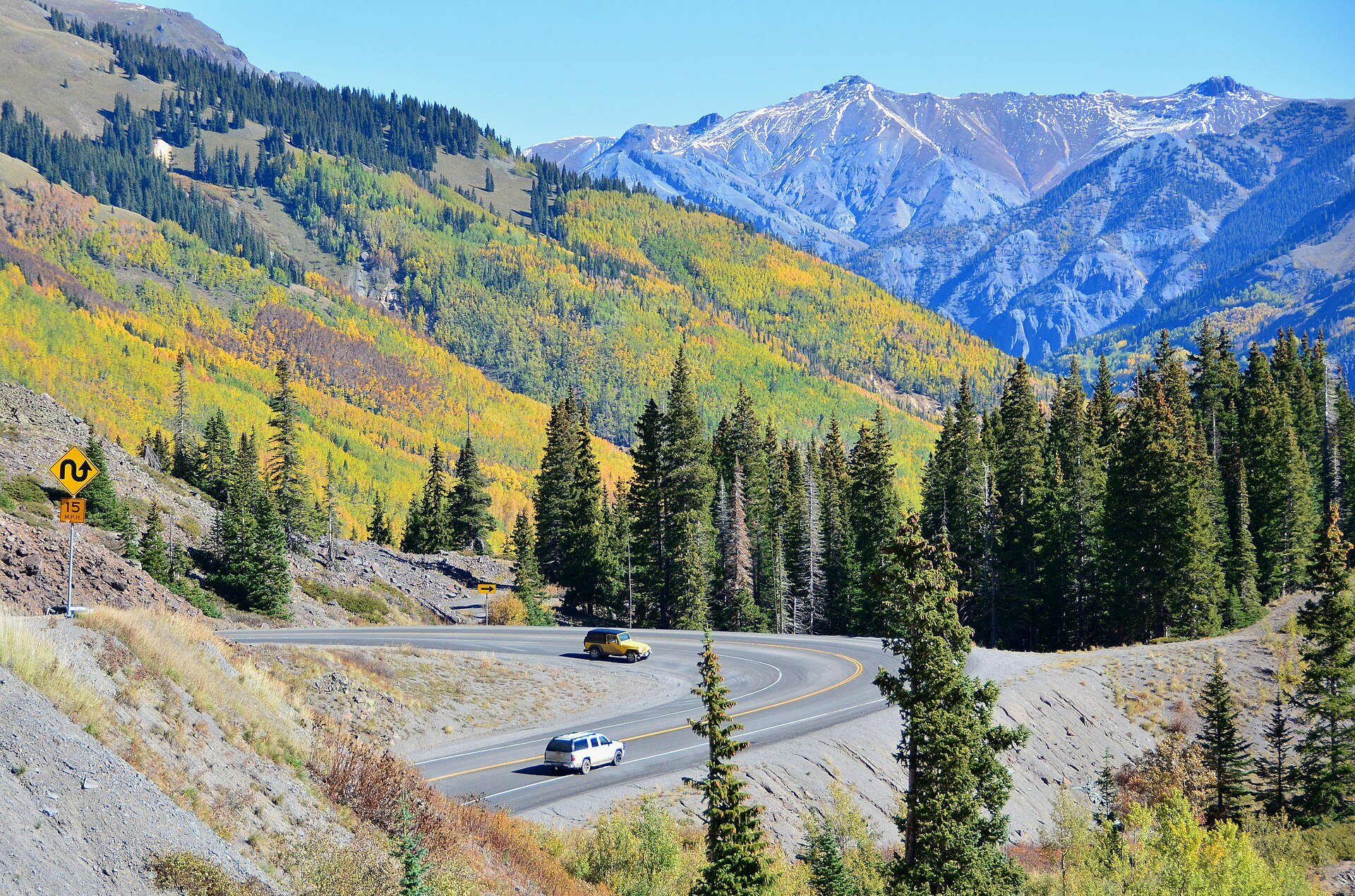 Cars on the Million Dollar Highway among fall colors and San Juan peaks between Silverton and Ouray