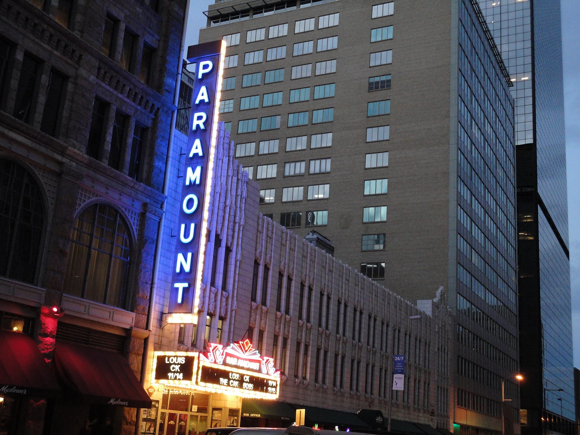 Paramount Theatre's neon vertical sign lit up at dusk on Glenarm Place